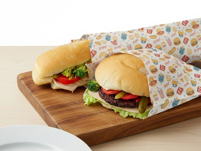 دو ساندویچ بر روی تخته که درون پاکت ساندویچ طرح دار هستند